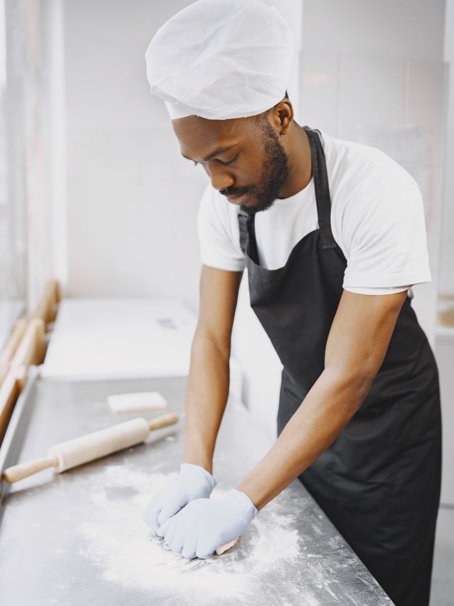 Baker shaping dough on a floured bench at Golden Crust Bakery